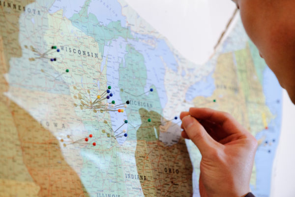 A soon-to-graduate medical student uses a push pin to mark on a United States of America map the destination of their just-announced residency