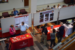The Department of Ophthalmology and Visual Sciences and the Optical Imaging Core are set up side by side. Staff from the DOVS talk to one another, while participants talk, looking at the Optical Imaging Core poster.