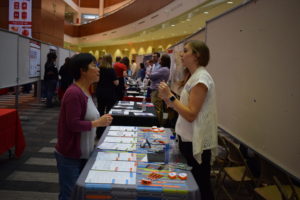 A vendor from Integrated DNA Technologies talks, gesticulating with her hands, to a BadgerConnect participant.
