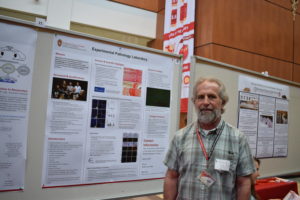 Joe Hardin stands in front of the Experimental Pathology Laboratory poster.
