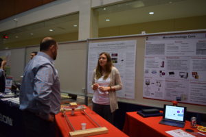 Jen Schehr talks to a BadgerConnector attendee in front of the Circulating Biomarker Core and Microtechnology Core posters.