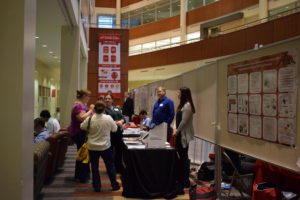 A group of people talk in front of the ThermoFisher table as vendors look on.