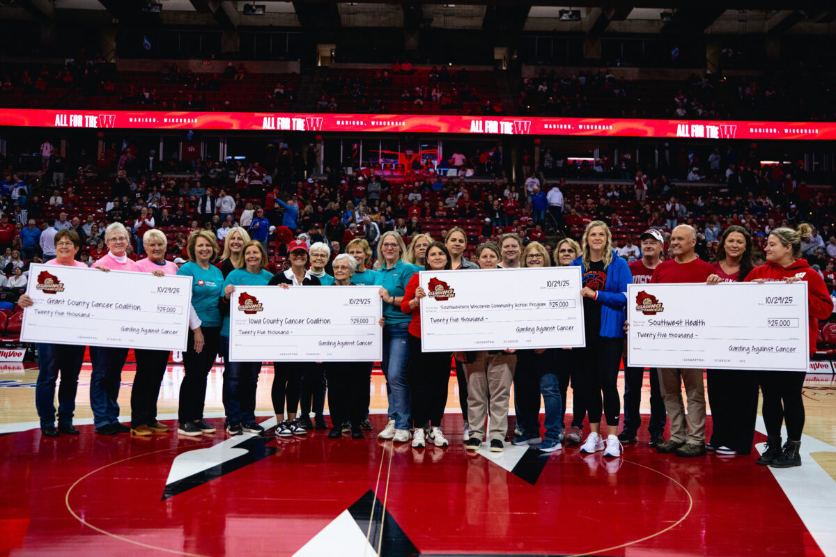 People hold four donation checks during Garding Against Cancer 2025 Exhibition Game.