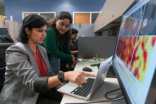 Dr. Tiwari pointing to image on laptop